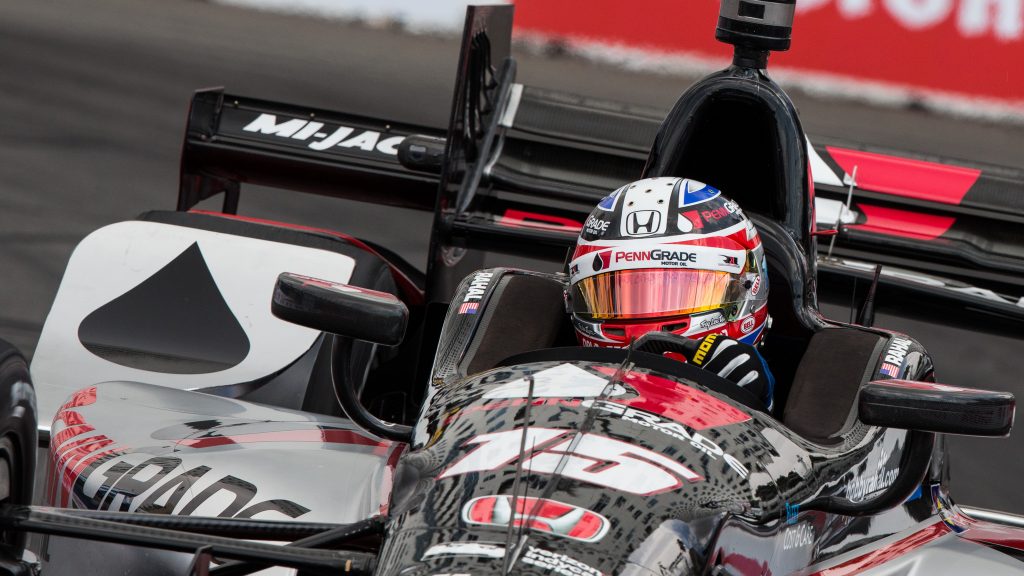 The skyscraper apartment buildings of downtown Long Beach reflect down the nose of Graham Rahal's polished racecar