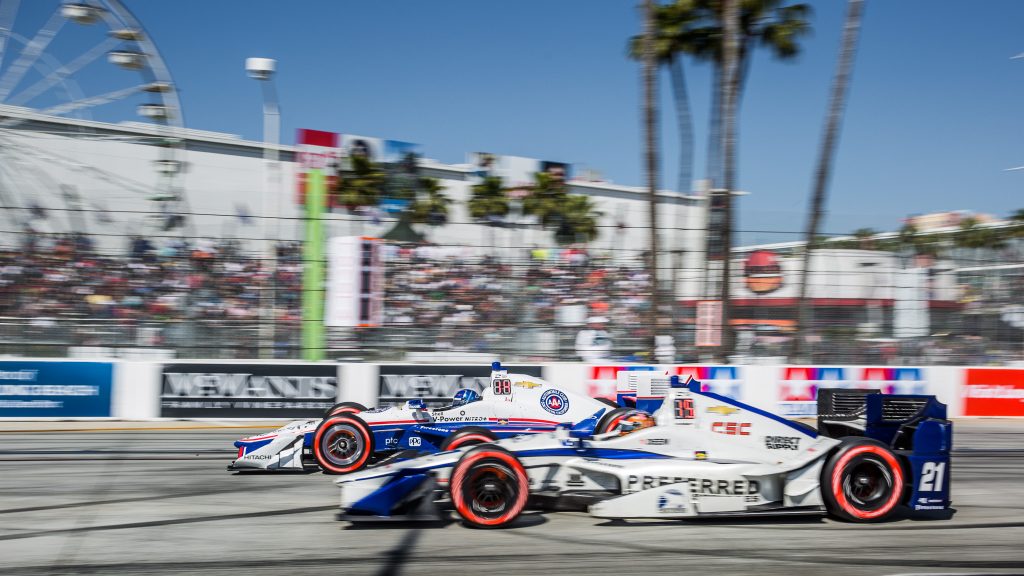 Helio Castroneves overtakes JR Hildebrand in front of the crowd and ferris wheel